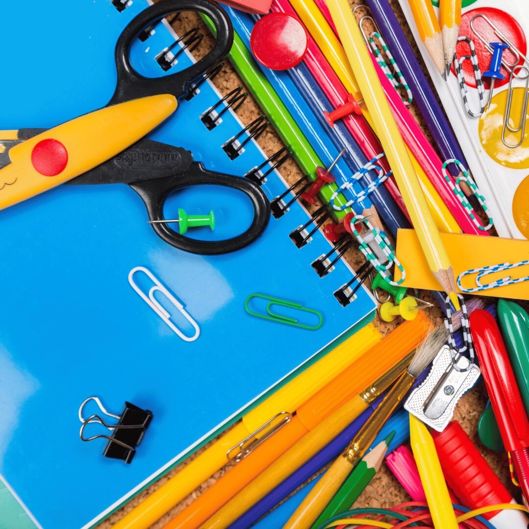 A colorful collection of school supplies, including wooden pencils, metal paper clips, and plastic scissors, with the text "Beginner - A2 Level General Conversation Course". This image is for a read4more.com lesson on how to describe the materials of objects.