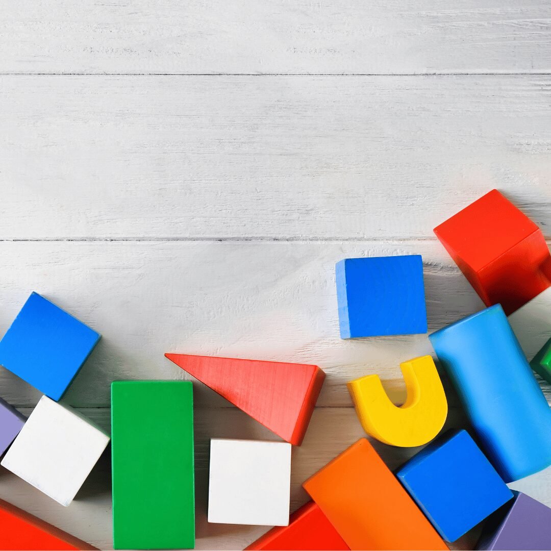 Colorful wooden blocks in various shapes (square, triangle, rectangle) on a white background, with the text "Beginner - A2 Level General Conversation Course". This is the featured image for a read4more.com lesson on how to describe shapes in English.