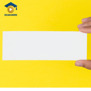 A hand holds a long, white piece of paper shaped like a rectangle against a yellow background. This image is a visual aid from read4more.com for a beginner's English lesson on describing shapes.