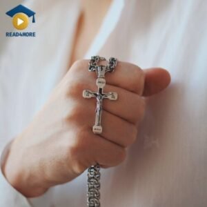 A close-up photo of a hand holding a shiny silver cross necklace, illustrating the material 'silver' for a beginner's English vocabulary lesson on read4more.com.