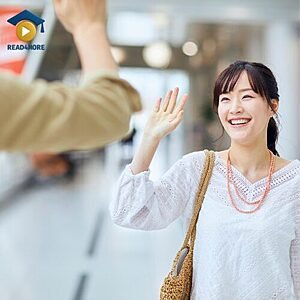 A smiling woman waving her hand to greet a friend, visually defining the basic English greeting "hello" for the Read4More online vocabulary glossary.