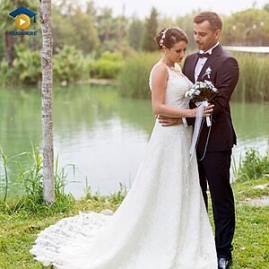 A bride and groom standing together by a lake on their wedding day, visually defining the English vocabulary word "married" (having a husband or wife) for the Read4More online glossary.