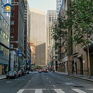 A view of a public road in a city with cars and buildings, visually defining the English vocabulary word "street" (a public road in a city or town) for the Read4More online glossary.